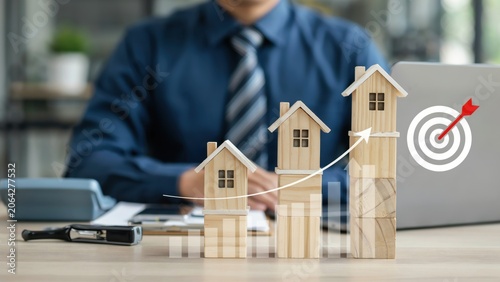 Real estate agent showing rising wooden house models representing property growth