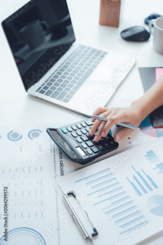 Accounting and Financial Analysis: A person's hands meticulously work a calculator, surrounded by financial reports, charts, and a laptop.