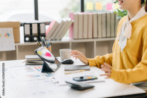 Digital Workspace: A focused individual is engrossed in a digital tablet, surrounded by documents, calculator, and office supplies, suggesting a modern approach to work and study.