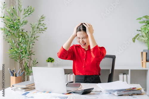 Bilde på lerret Frustration at Work: A stressed woman grips her head in despair as she stares at her laptop, overwhelmed by tasks and deadlines in her office