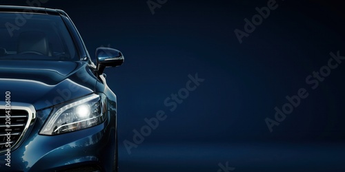 Close-up of a modern blue car's front headlight and grill on a dark background.