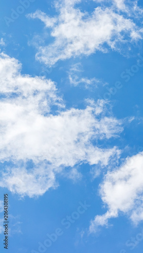 White cumulus clouds floating in bright blue sky. Clear weather atmosphere background
