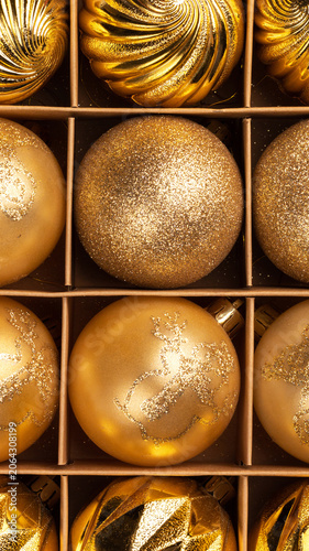 Collection of various gold Christmas ornament in box, with glitter, shiny, and faceted designs for holiday season decoration, overhead view