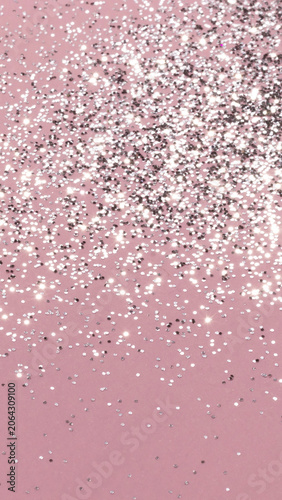 Silver glitter particles falling over pink background. Festive holiday decor and celebration backdrop