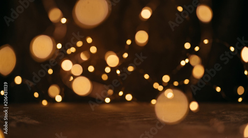 Warm golden bokeh lights reflecting on dark textured surface.