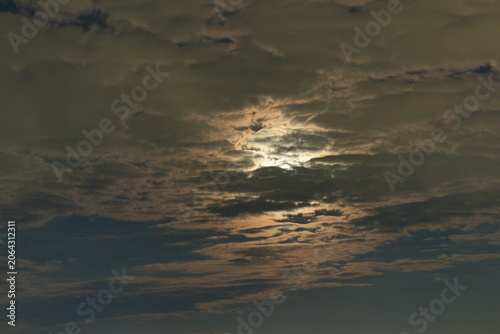 The moon shines from behind the clouds.