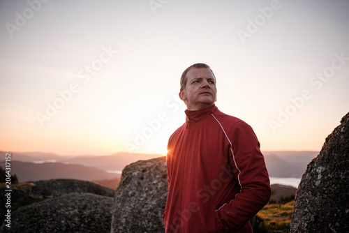 Obraz na plátne Man contemplating at sunset on mountain peak