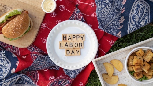 Happy Labor Day Picnic Flat Lay with Burger and Snacks on Red Patterned Blanket