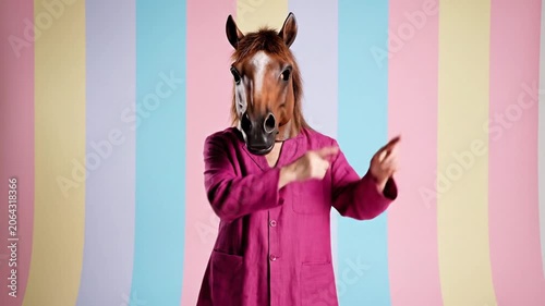 A horse wearing a pink coat standing in front of colorful stripes.