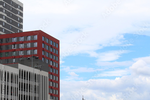 a modern beautiful residential building with a red facade against a clear blue sky	