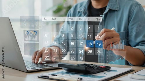 Person using a laptop and calculator to plan a business schedule on a calendar