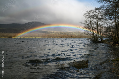 Obraz na plátně Vibrant rainbow over Coniston Water under a dramatic stormy sky with choppy dark