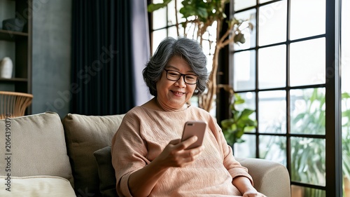 Senior woman using smartphone at home, represents modern technology adoption, communication, and an active lifestyle among older adults.
