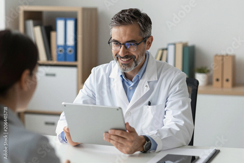 Doctor reviewing medical records on tablet with patient