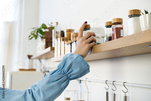 Принти на полотні Beautiful woman reaching for spices in a cozy home kitchen filled with natural l