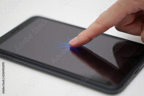 Finger pressing touchscreen smartphone with glowing light effect