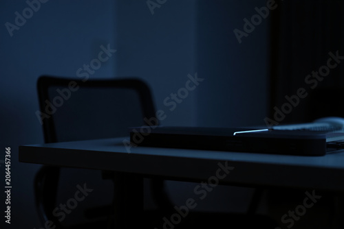 Dark room with desk and chair, router or electronic device on table