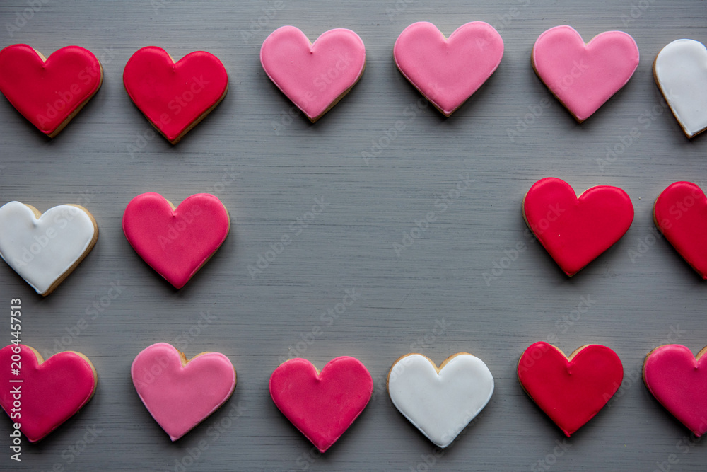Fototapeta premium Heart-shaped cookies in red, pink, and white on a gray surface.