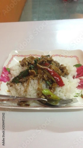 A panning, close-up shot of one of the most popular dishes in Thailand, stir fried holy basil with pork (Pad Kaprao Moo).