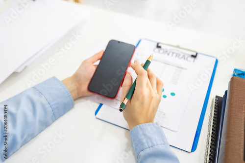 Fotografie Person holds phone and pen over documents