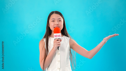 Girl holding microphone pointing to side on blue background
