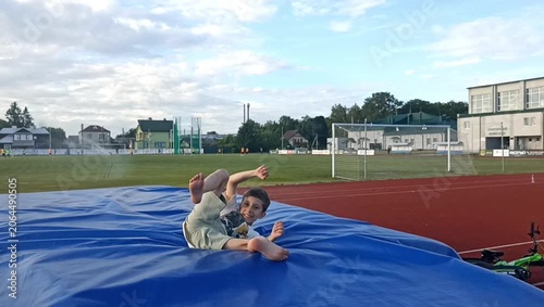 Active boy performs an acrobatic  front flip on an outdoor sports playground. Healthy childhood activity, fitness training, agility and athletic movement in the fresh air.