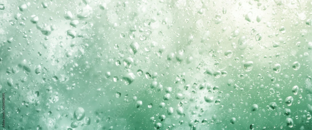 Fototapeta premium Water droplets on a green glass surface