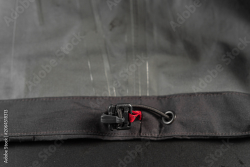 Quadro su tela Plastic toggle stopper with elastic bungee cord inside a black jacket, close up of adjustable waist drawstring fastener on clothing