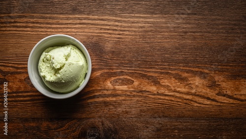 Pistachio ice cream in a white bowl on wooden table