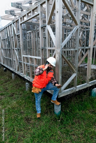 Civil engineer in safety vest and hard hat coordinating site development on a mobile phone