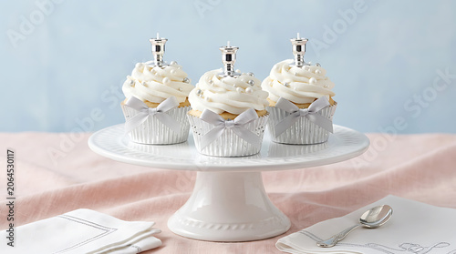 Three cupcakes presented on a white cake stand on a pink tablecl