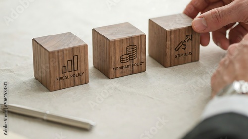 Wooden blocks labeled fiscal policy monetary policy and stimulus on table
