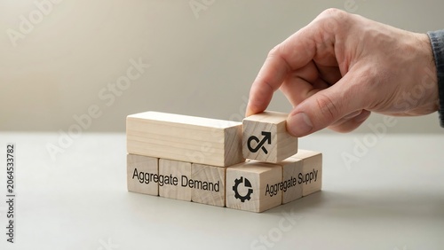 Hand adjusting wooden blocks labeled aggregate demand and supply