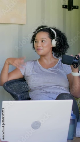 Vertical video: Recording woman headset speaking gesturing at mic at home laptop for podcast