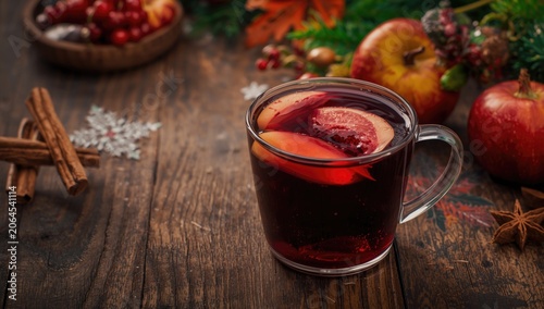 Mulled wine with apple slices and cinnamon on wooden table