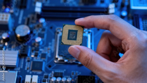 Hand holding microchip over circuit board