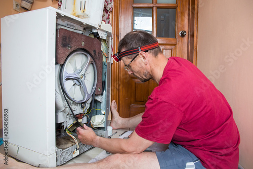 A man repairs a washing machine himself.