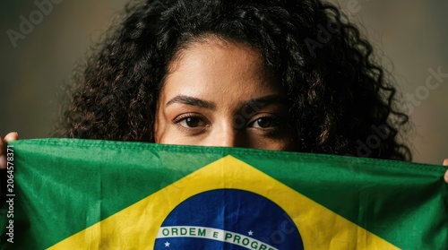 Brazilian woman partially obscured by national flag intense gaze