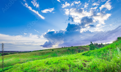 Fotografie Vibrant green hills roll beneath a dramatic sky