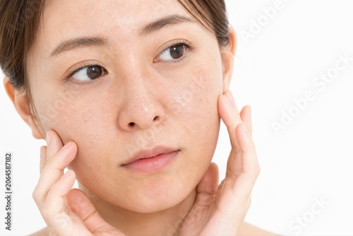 頬の両手で頬の肌を確認する女性の肌悩み