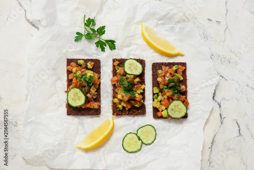 Salmon tartare with avocado and cucumber on pumpernickel rye bread.