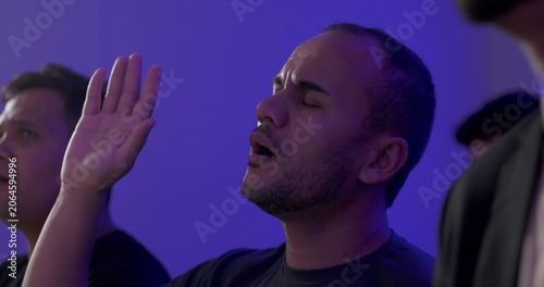 Obraz na plátně Hispanic man with raised hand and intense expression worshipping during evangeli
