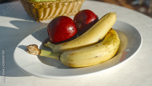 Two bananas and two apples on a white plate