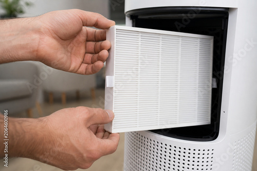 Close-up of hands installing a clean white filter in a home air purifier, showing appliance maintenance and indoor air quality care.