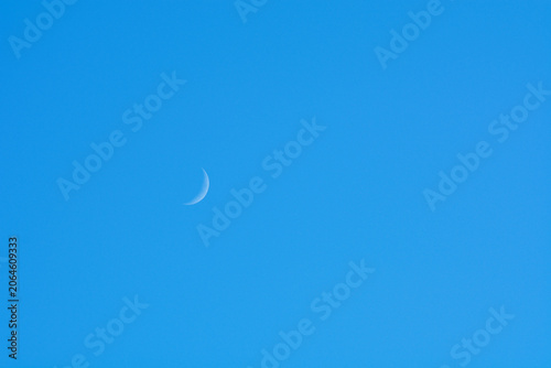 Crescent moon in a clear blue sky with copy space