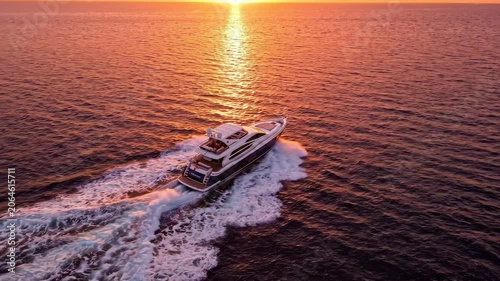 Aerial view of a luxury motor yacht cruising on the open ocean at sunset