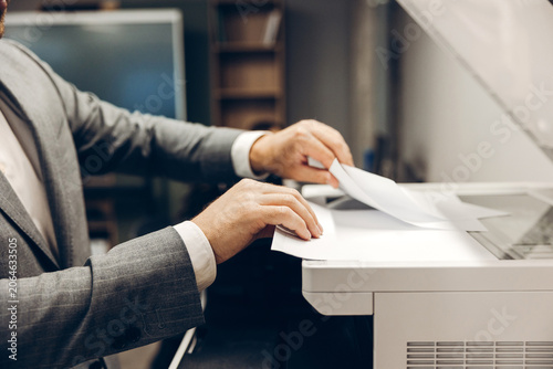 Foto Businessman's hands copying document on office multifunction printer