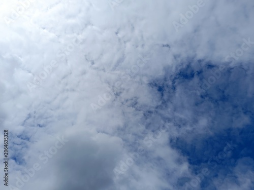 Bright blue sky interspersed with fluffy white clouds. Daytime meteorological background with natural light