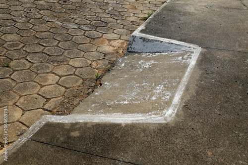 Worn concrete ramp with white stains and cracks next to hexagonal block pavement structure