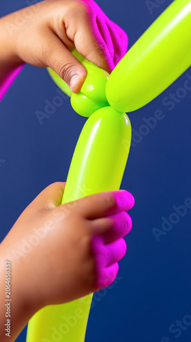 Child creating neon balloon art with bright green balloons on blue background